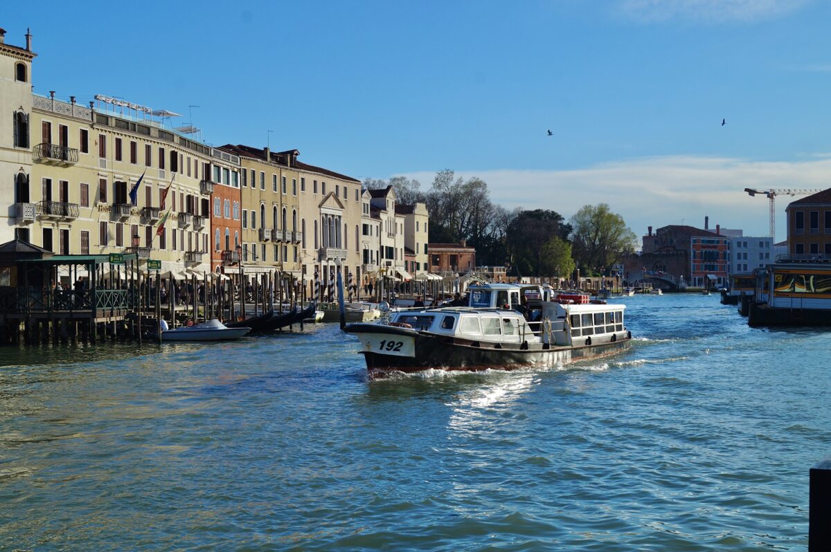 Urlaubsbild: Ein Schiff fährt durch azurblaues Wasser dahinter alte Häuser Venedigs